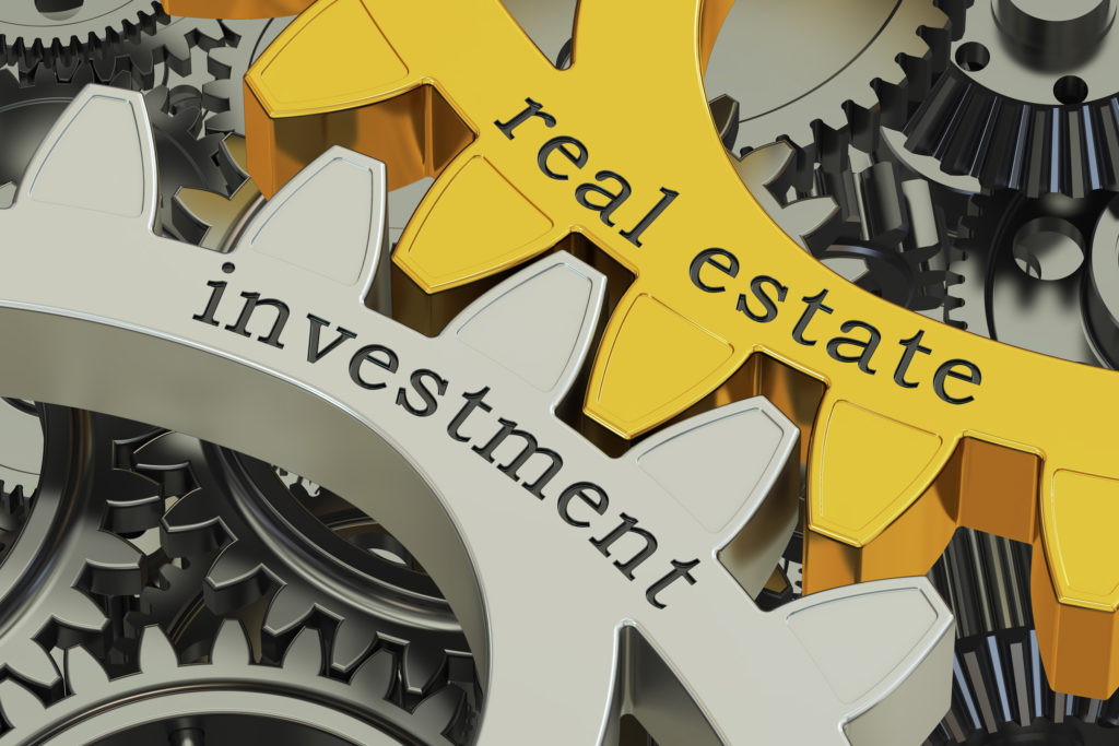 gray gear with the word "investment" next to yellow gear with "real estate" written